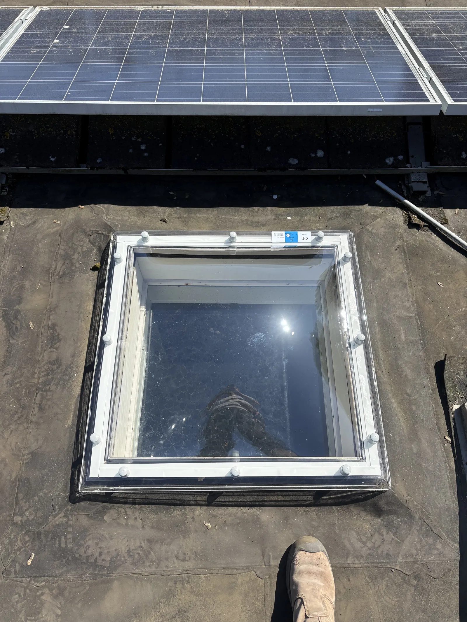 Dakraam in een plat dak naast zonnepanelen
