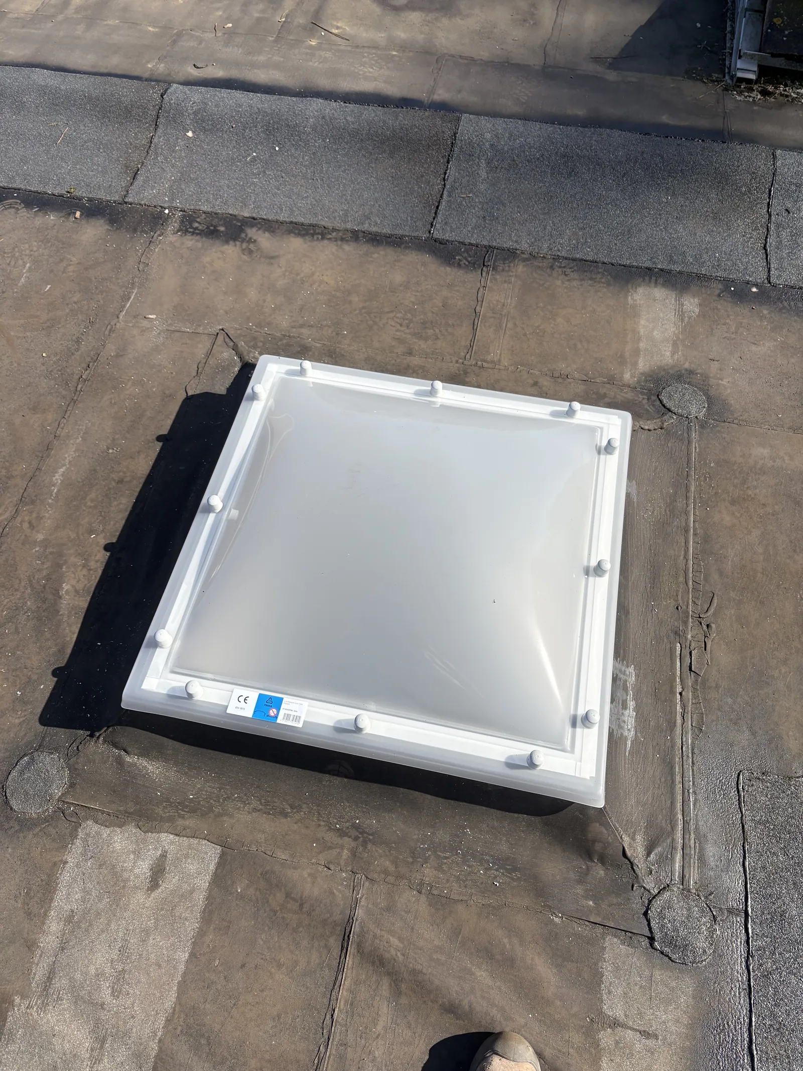 Nieuwe lichtkoepel op een plat dak met de dakbedekking eromheen doorgezet