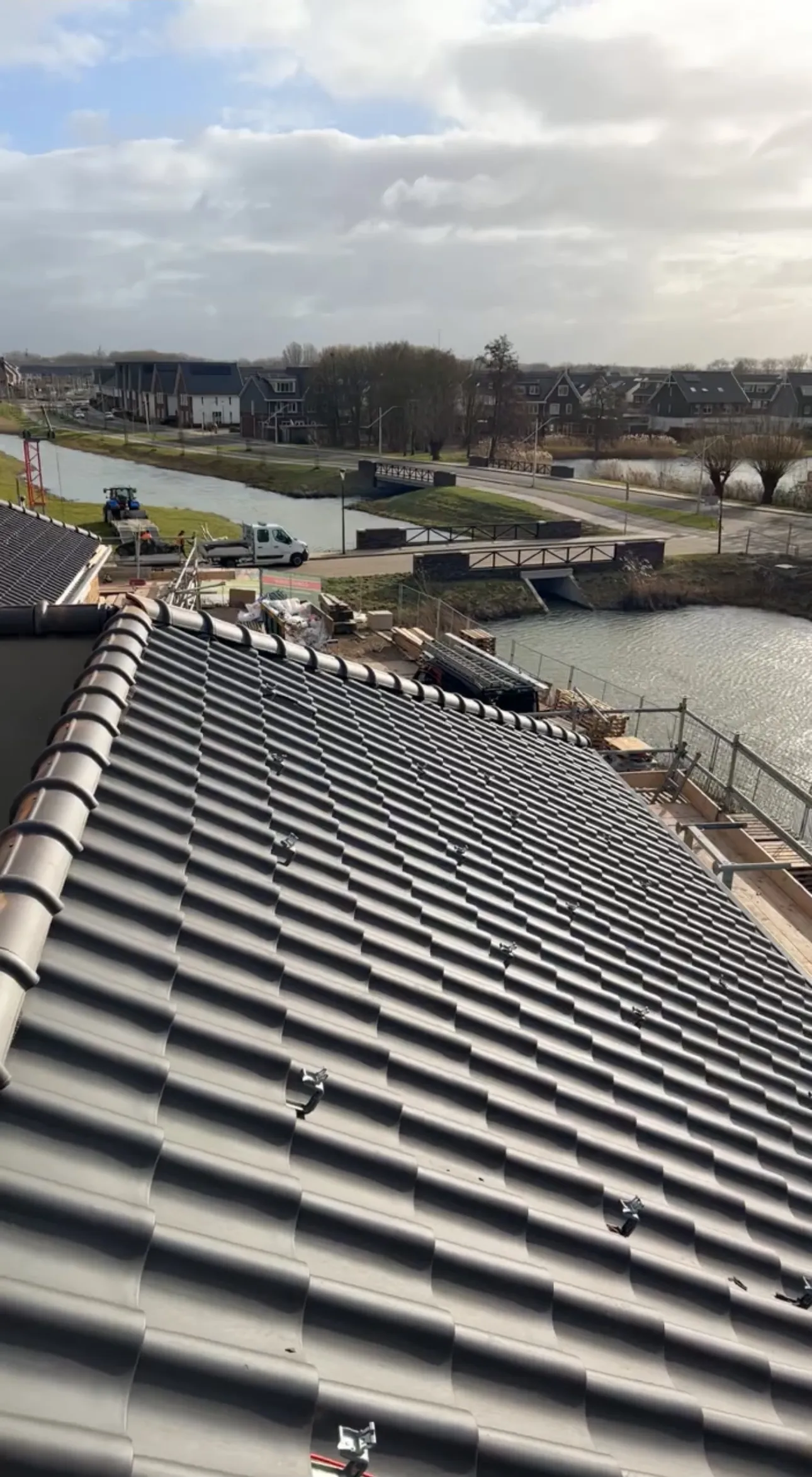 Nieuw antraciet pannendak, strak in rijen gelegd, met uitzicht over het water
